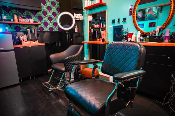 Interior of Timberlodge Parlor barbershop featuring vintage barber chairs, teal accent walls, mirrors, and professional styling equipment