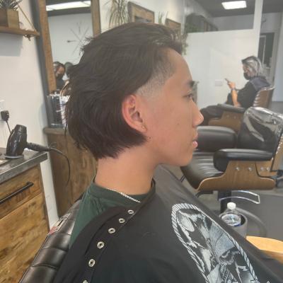 Man with a short skin fade haircut viewed from behind, wearing a graphic t-shirt, barbershop setting