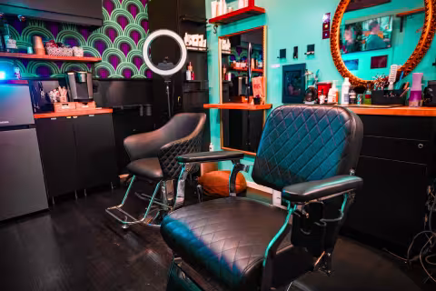 Interior of Timberlodge Parlor barbershop featuring vintage barber chairs, teal accent walls, mirrors, and professional styling equipment