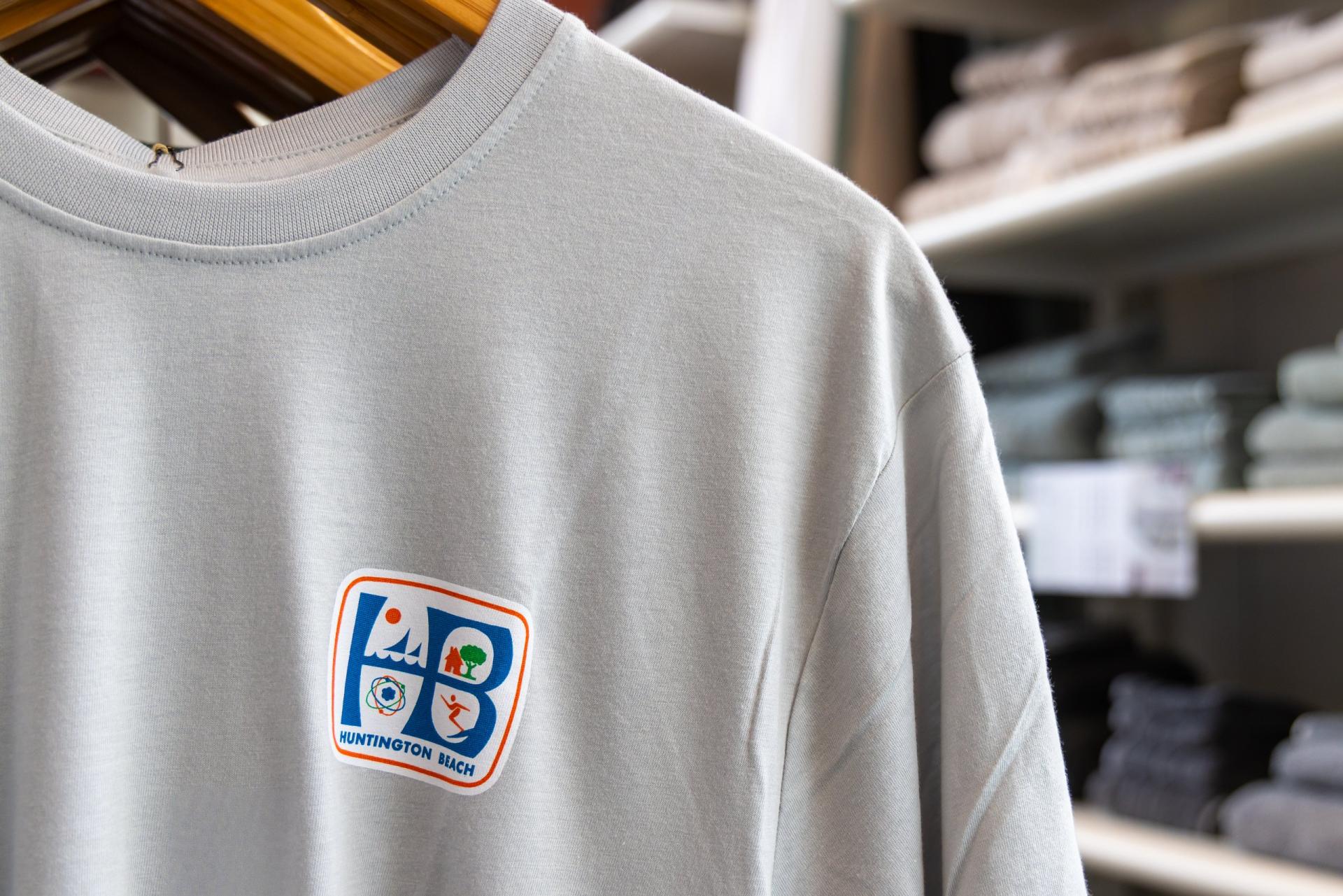 A gray T-shirt on a hanger shows the Huntington Beach city logo on the chest.